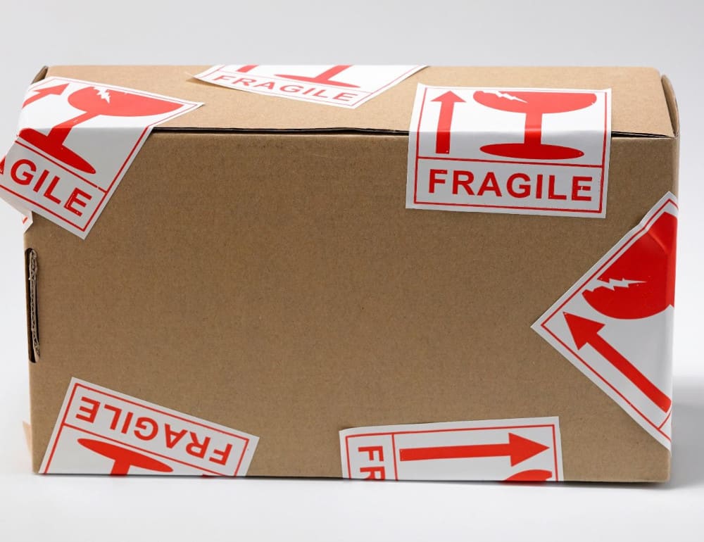A cardboard box with red and white fragile stickers