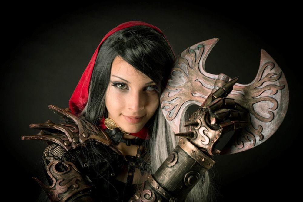 Close up of a female cosplayer wearing armor and holding a weapon.
