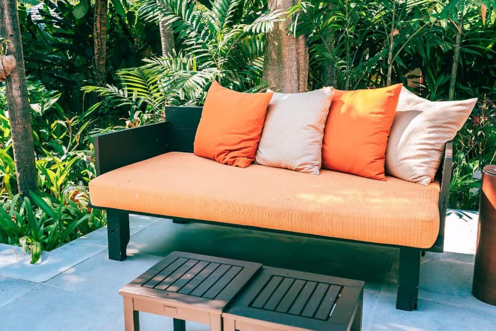 Outdoor daybed with orange seat cushion and pillows