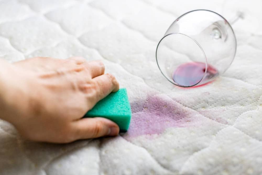 A person cleaning a mattress with a sponge