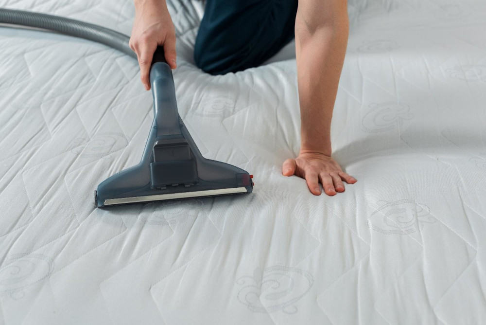 A person vacuuming a mattress