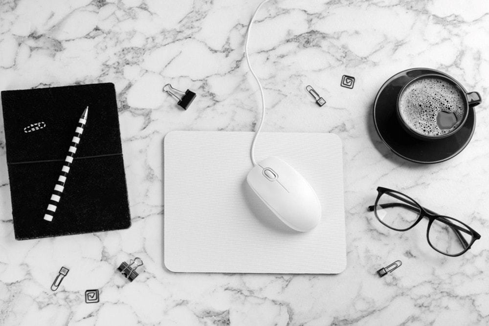 A mouse, mousepad and notebook on a marble desktop