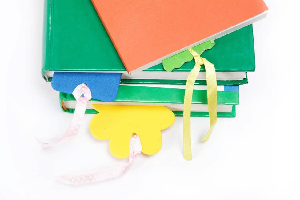 A stack of three books, each with a homemade bookmark made of foam and ribbon.