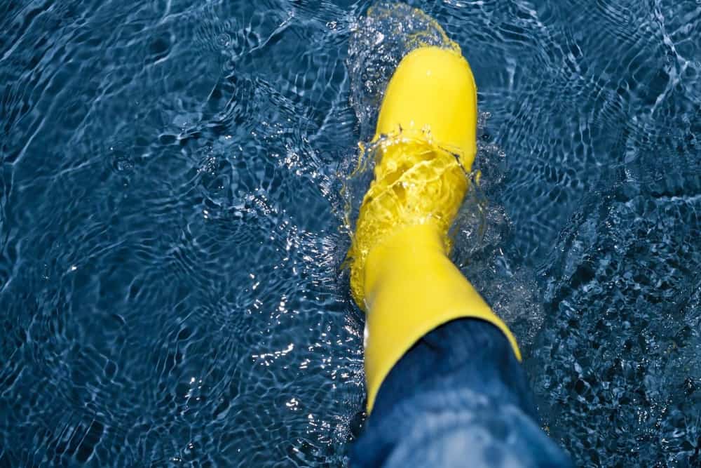 A person in a yellow rain boot stepping in water