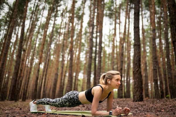 A person doing plank in the woods on a camping mat