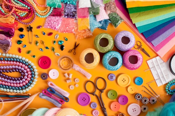 A table full of craft supplies including beads, buttons, scissors and yarn.