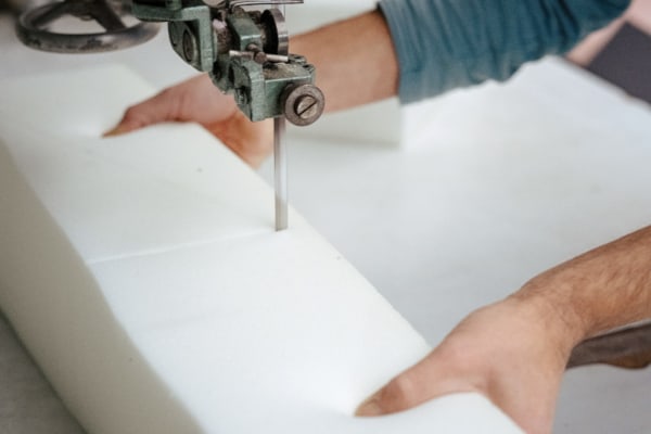 Cutting a piece of foam with a foam cutter saw.