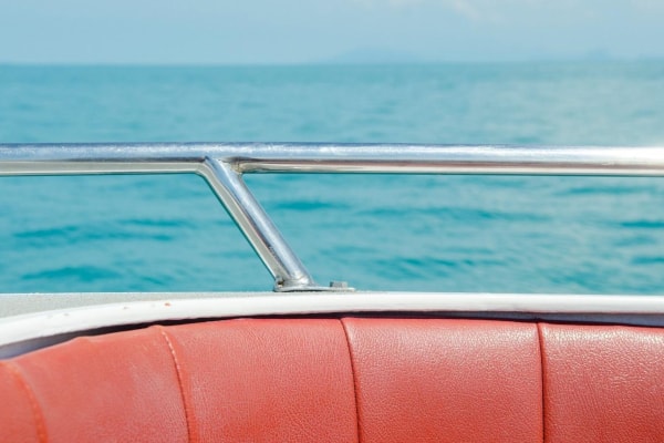A close-up of upholstered boat seating and metal railing of a boat
