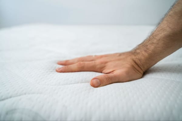 Hand pushing down on memory foam mattress