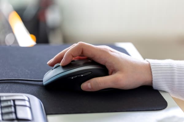 A hand using a mouse on a neoprene mousepad