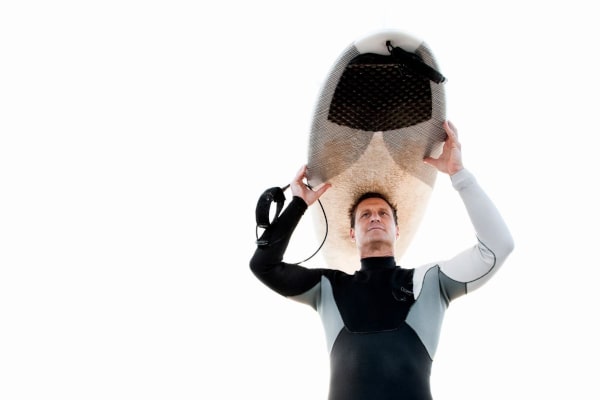 A person wearing a neoprene wetsuit holding a surfboard