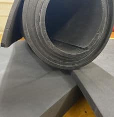 A dark grey roll of Cross-Poly foam on top of foam sheets