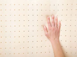 Right hand pressing on top of yellow perforated foam mattress