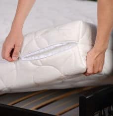 Two hands lifting up white mattress from bed frame