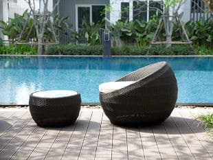 Black weave chairs with white cushions in front of outdoor pool