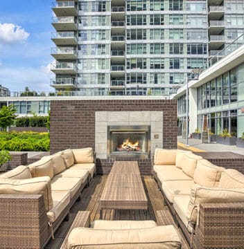 Wicker couches with yellow cushions on deck in front of fireplace