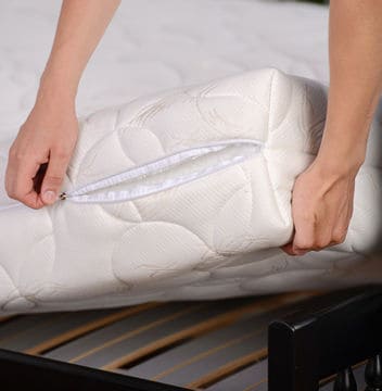 Two hands lifting up white mattress from bed frame