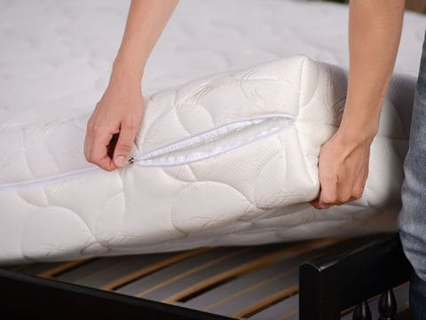 Two hands lifting up white mattress from bed frame