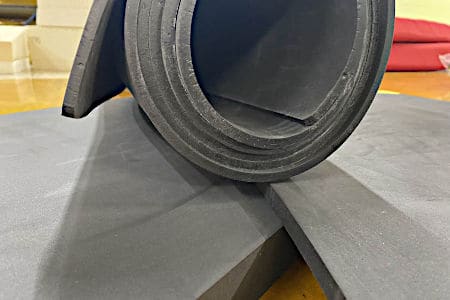 A dark grey roll of Cross-Poly foam on top of foam sheets