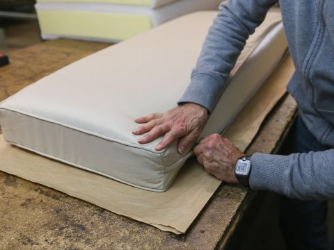 Custom covers being put on a foam cushion by worker