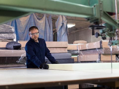 man wearing glasses in warehouse moving large block of foam