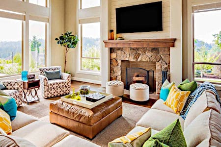 Clean and brightly lit living room with ottoman, couch and chairs with a side table