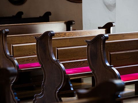 Brown wood church pews with red seat cushions