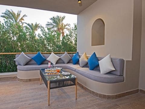 Curved outdoor couch with grey, blue and white pillows on a balcony in front of a coffee table