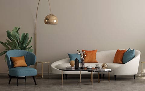 Circular white couch in front of a coffee table with two blue chairs and house plants on either side