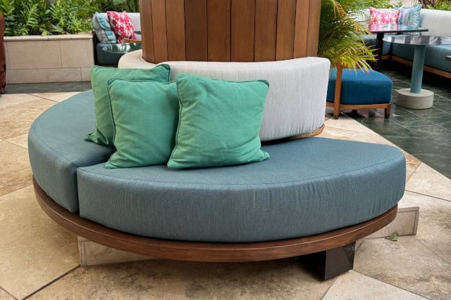  Black metal patio furniture with white cushions on a deck in front of a brick wall