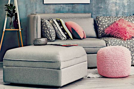 Grey ottoman and couch in room with pink decorative accents