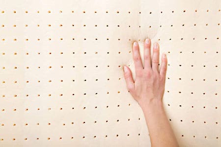 Right hand pressing on top of yellow perforated foam mattress