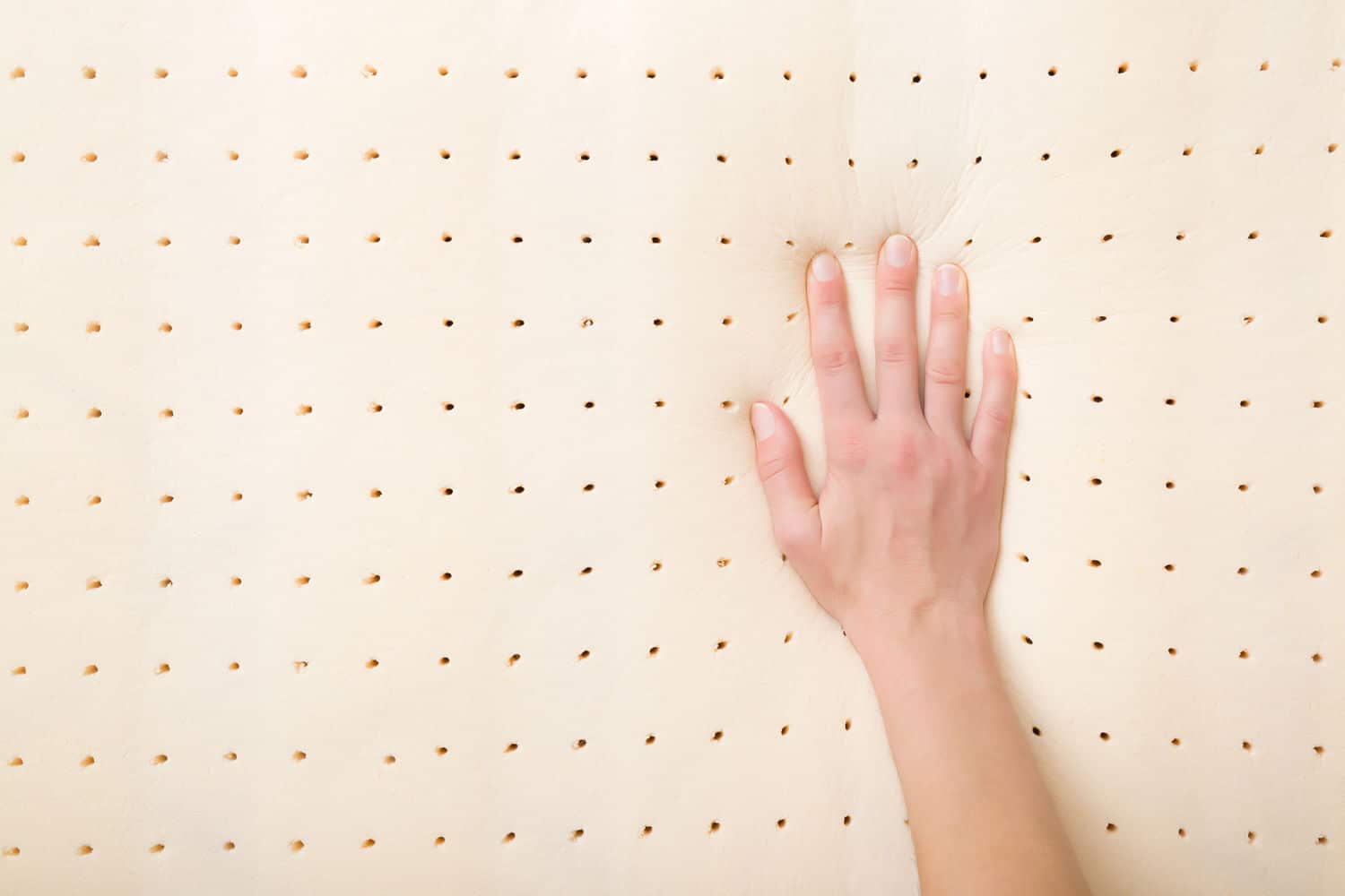 Right hand pressing on top of yellow perforated foam mattress