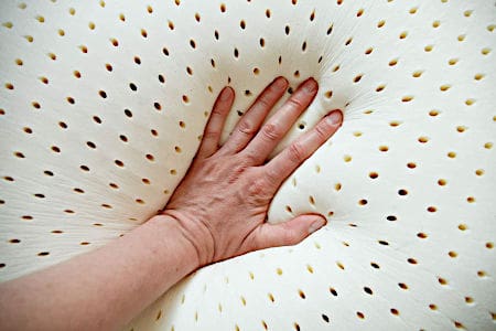 Perforated latex pillow with hand pushing down in the middle