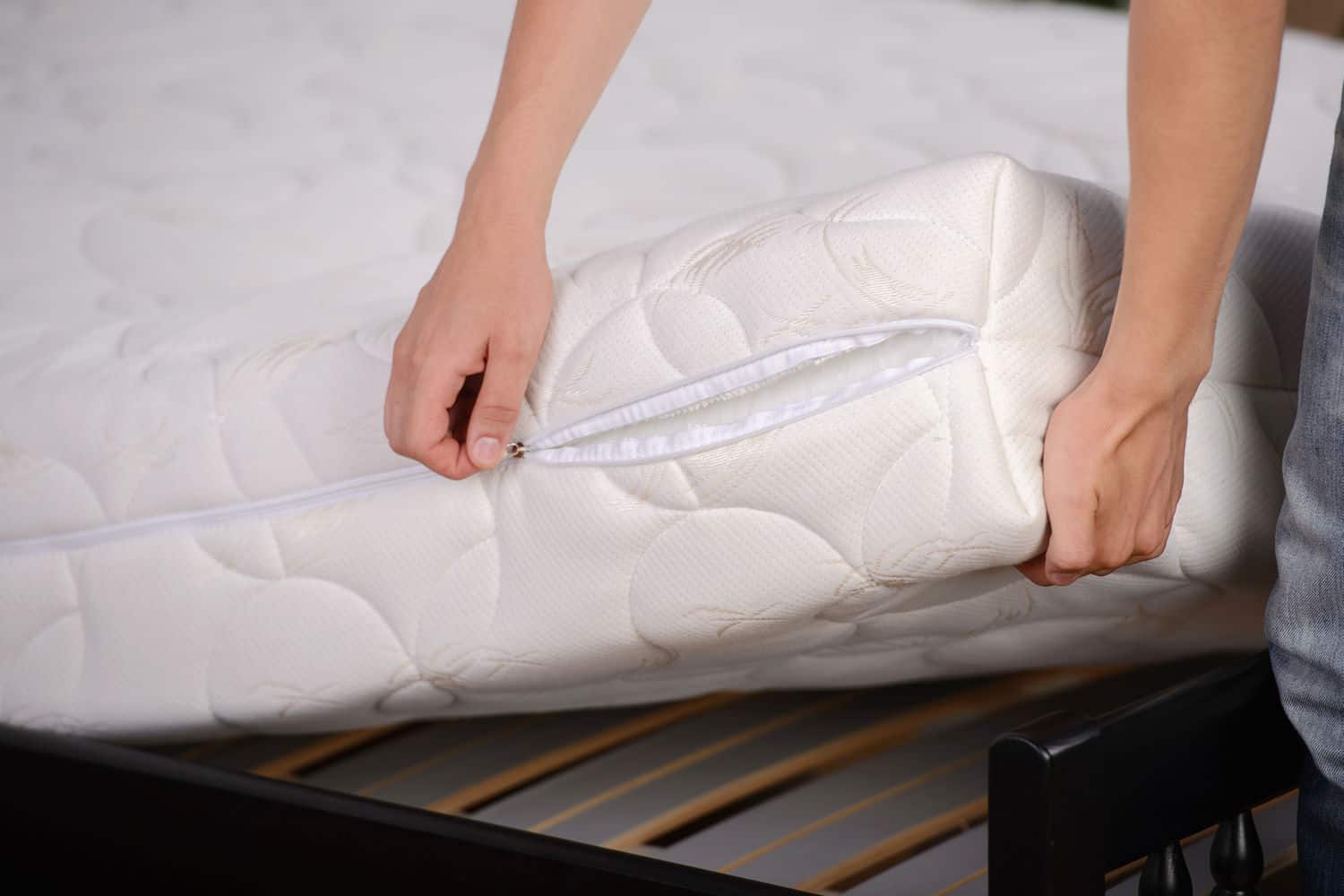Two hands lifting up white mattress from bed frame