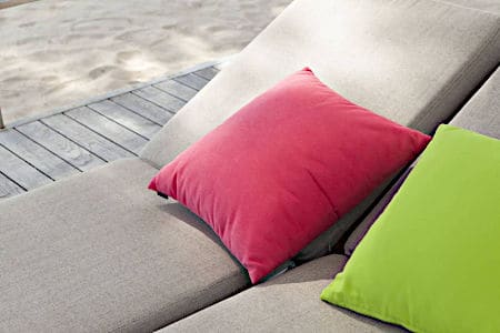 Bright pink and green pillows on tan lounge chairs