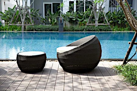 Black weave chairs with white cushions in front of outdoor pool