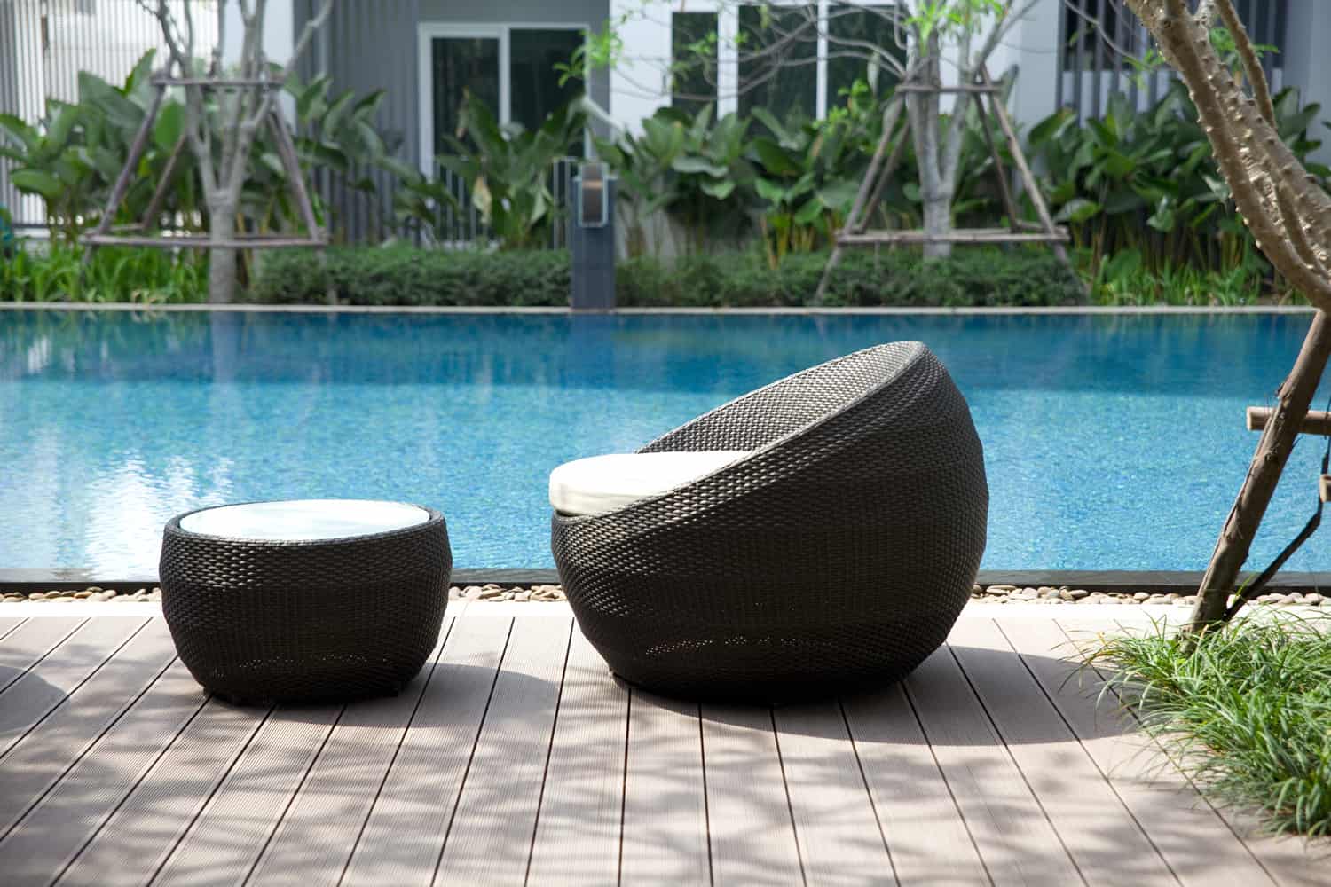 Black weave chairs with white cushions in front of outdoor pool