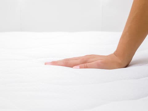 Hand resting on white spring mattress